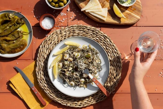 Prato tradicional da Ligúria com frutos do mar, pimentões grelhados, azeitonas e queijo servido em um ambiente mediterrâneo.