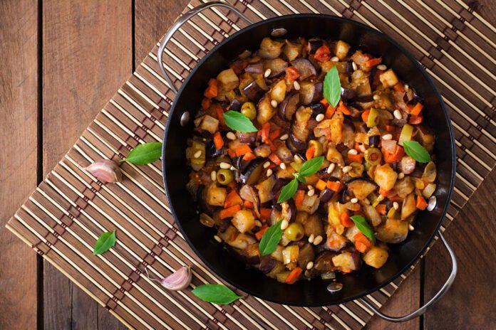 Panela com caponata siciliana, um prato vegetariano italiano feito com berinjelas, tomates, azeitonas, alcaparras e temperos frescos.